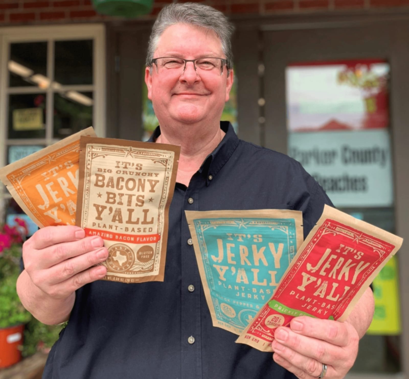 Brett Christoffel, founder and CEO of All Y’all Foods, holding four packs of plant-based jerky